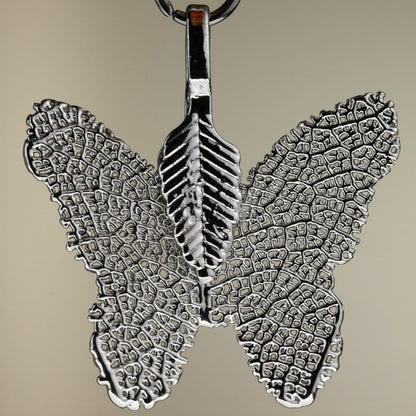Close detail of the silver-coloured filigree butterfly charm from the Blood Moon bracelet set