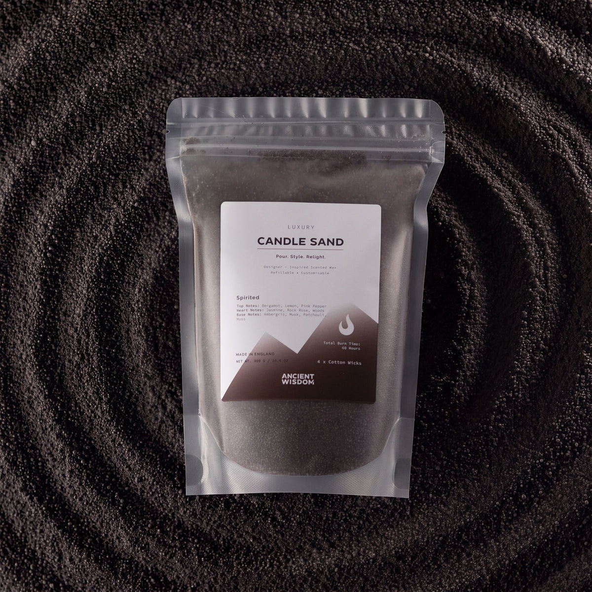 Spirited fragranced candle sand in black, 300g, in a resealable pouch on swirled sand