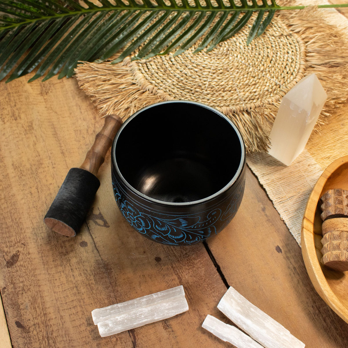 Alternative angle of the blue cauldron bowl styled with palm leaves, mallet and selenite