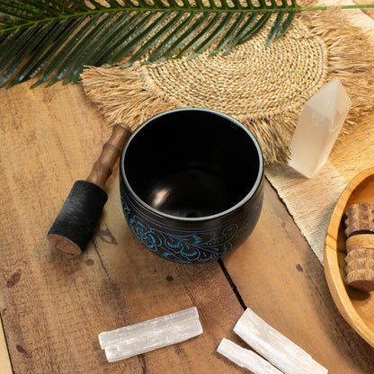 Alternative angle of the blue cauldron bowl styled with palm leaves, mallet and selenite
