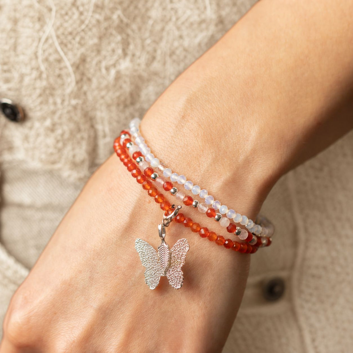 Blood Moon bracelet stack worn on the wrist with a cream knit sleeve, alternative angle